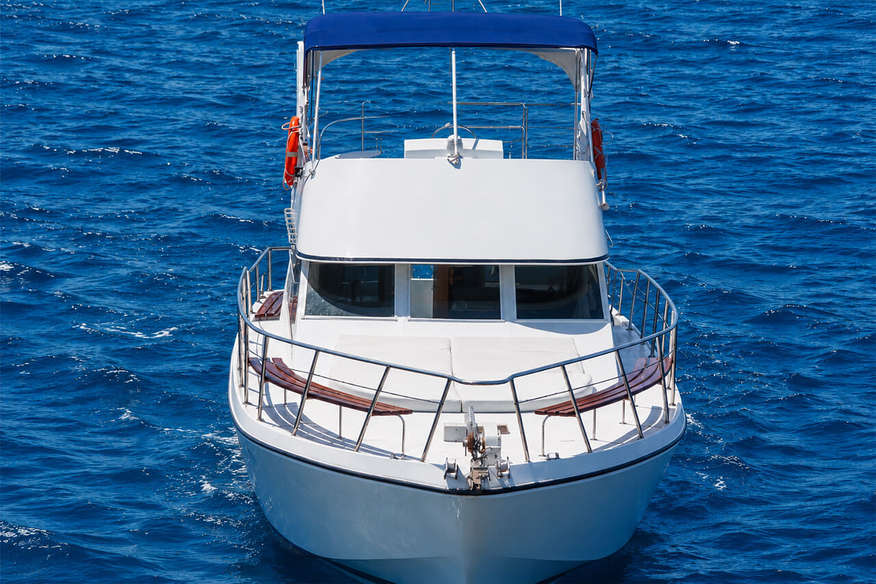 A clean front view of the white Neptuno motor yacht floating on deep blue Atlantic water, with no guests visible and the boat as the clear central subject.