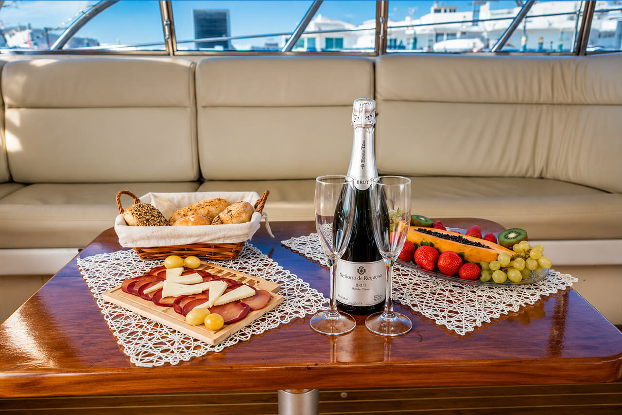 A selection of bread, cheese, cured meats, fresh fruit and chilled cava served inside Neptuno for guests to enjoy during their Tenerife boat experience.
