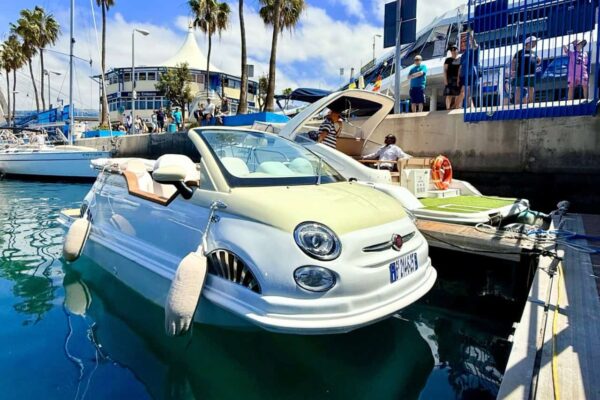 Fiat 500 sin matrícula flotando tranquilamente junto al muelle bajo un cielo soleado