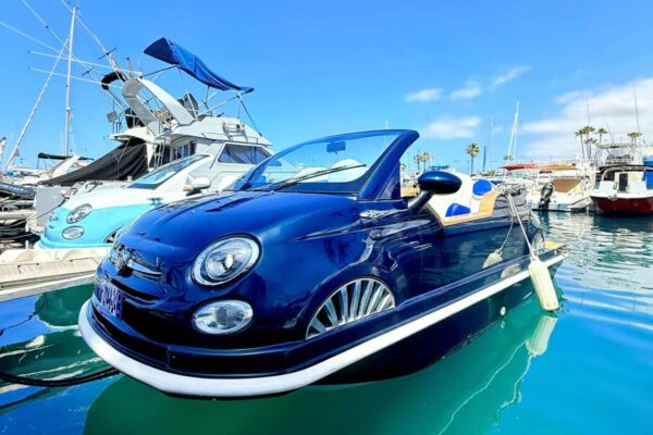 Elegante barco Fiat azul oscuro atracado en el puerto deportivo Puerto Colon rodeado de yates y palmeras