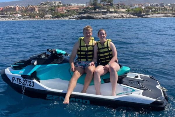 Smaidošs pāris sēž uz Seadoo ūdens motocikla Costa Adeje Tenerifes ekskursijas laikā