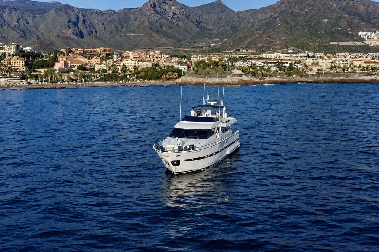 Paladio luxury yacht cruising off the Tenerife coast during a private charter, with Costa Adeje and the mountains in the background.