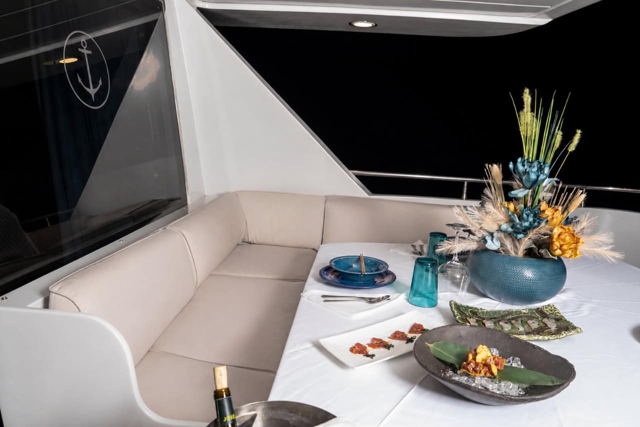 Elegant table prepared for a private yacht dining experience in Tenerife, with plated dishes, wine glasses and a formal dinner setting on board.