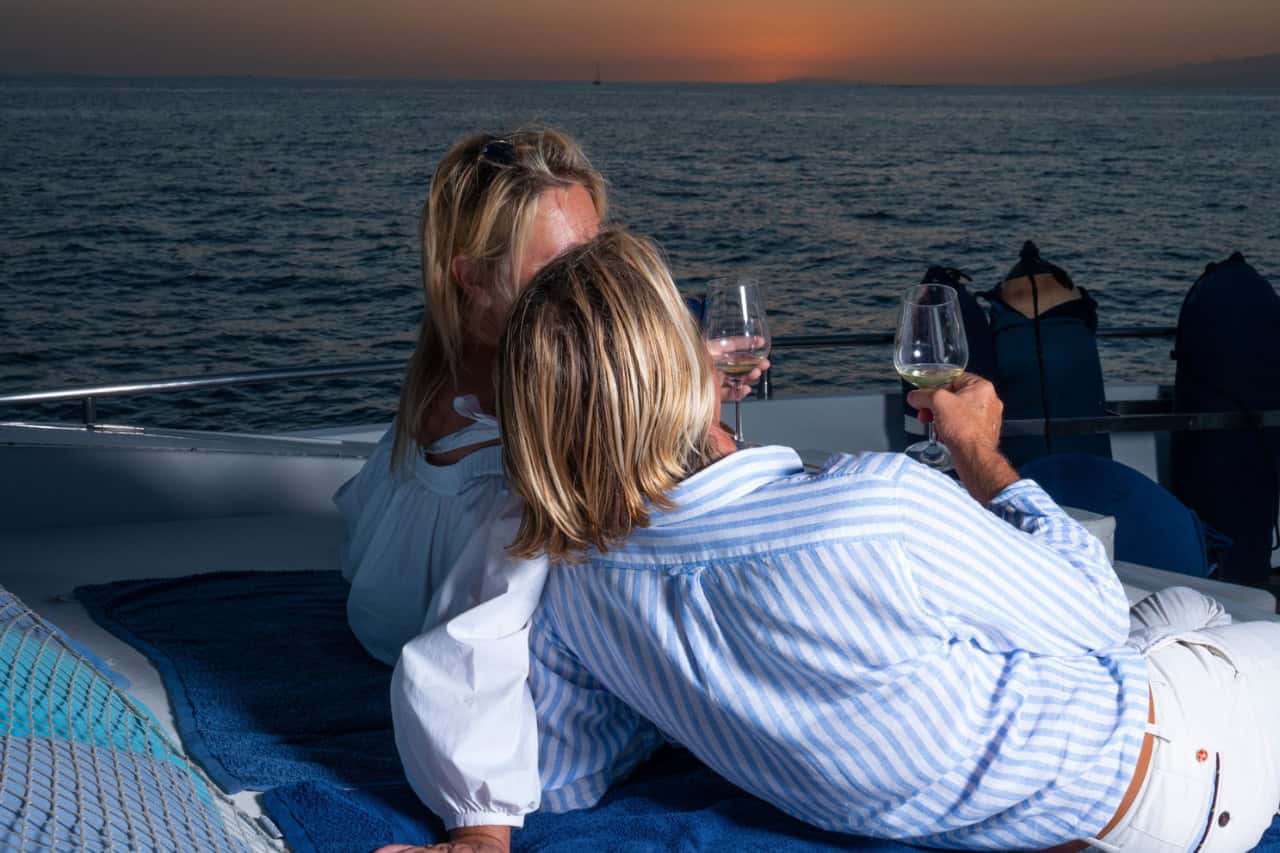 Couple relaxing with glasses of wine during a private sunset yacht experience in Tenerife, ideal for romantic celebrations and special occasions.