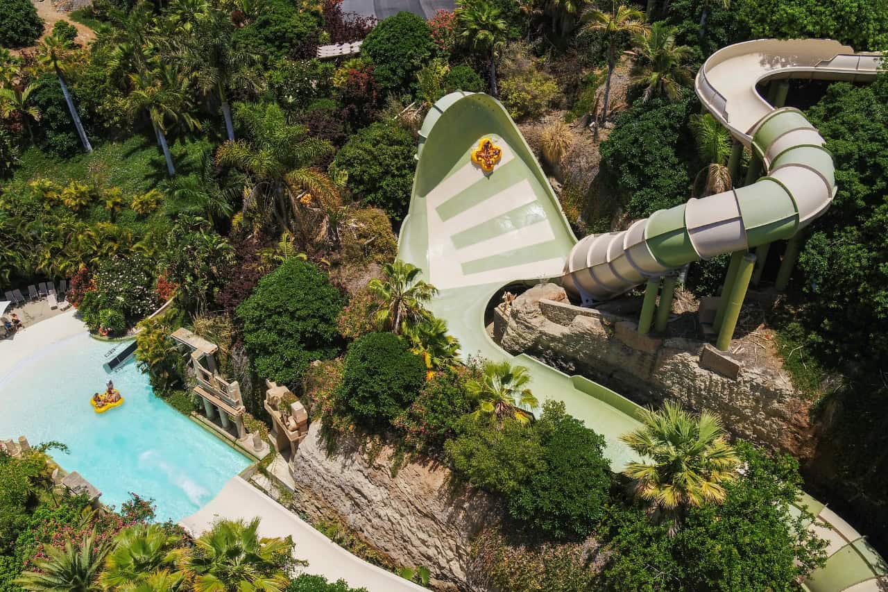 Guests riding a raft slide through tropical scenery at Siam Park