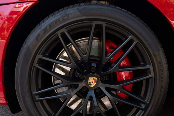 Porsche Macan GTS melnā vieglmetāla diska tuvplāns ar Pirelli P-Zero riepu un sarkanu Porsche bremžu suportu.