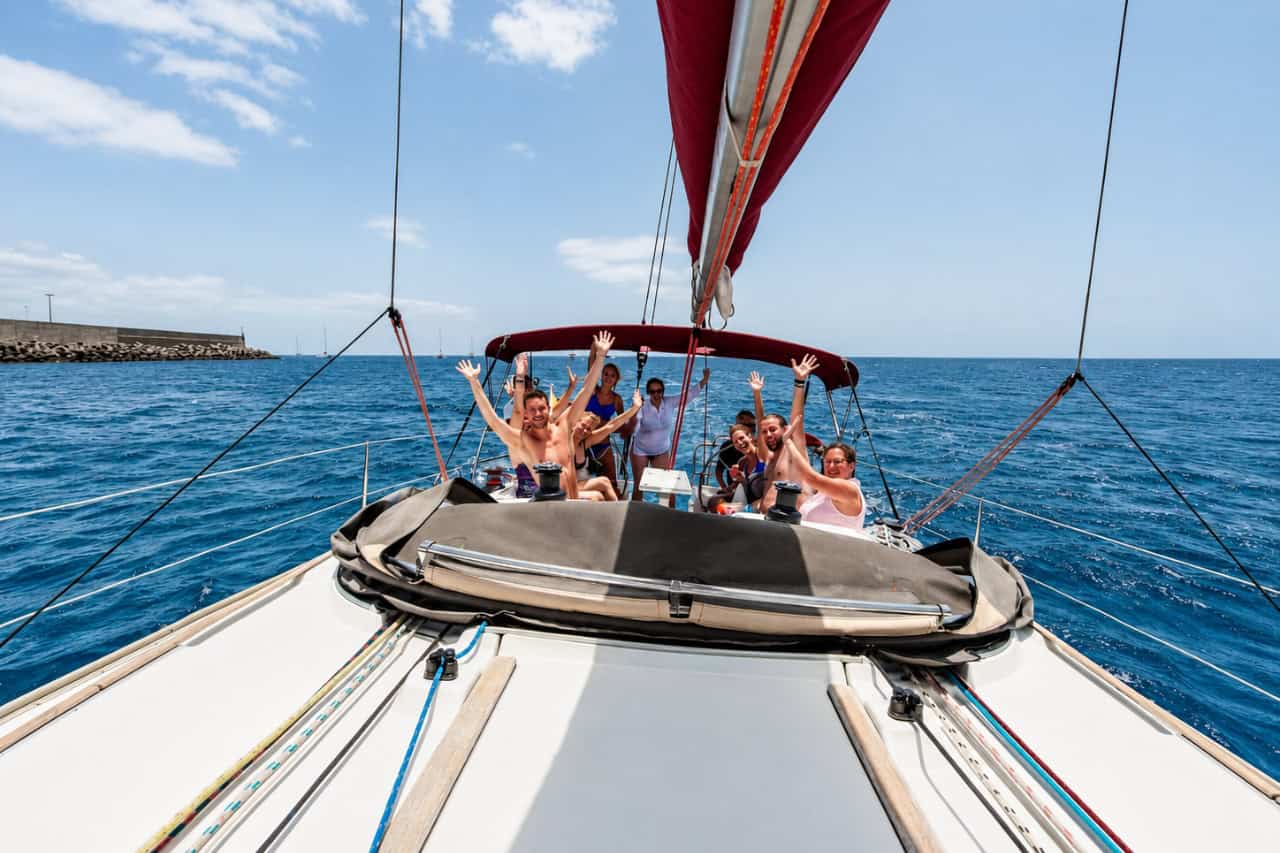 Happy group waving from the cockpit of a sailing yacht during a boat trip in Fuerteventura