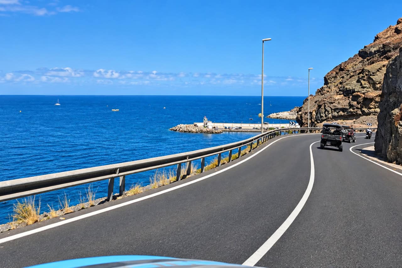 The buggy convoy driving a paved coastal road with cliffs and ocean views in Gran Canaria