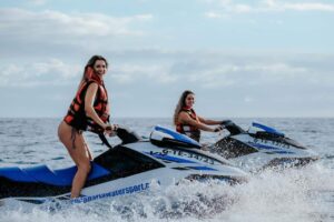 Deux femmes aventureuses s'amusent à faire du jet-ski ensemble dans les eaux de la côte de Gran Canaria, profitant de l'excitation de la mer.