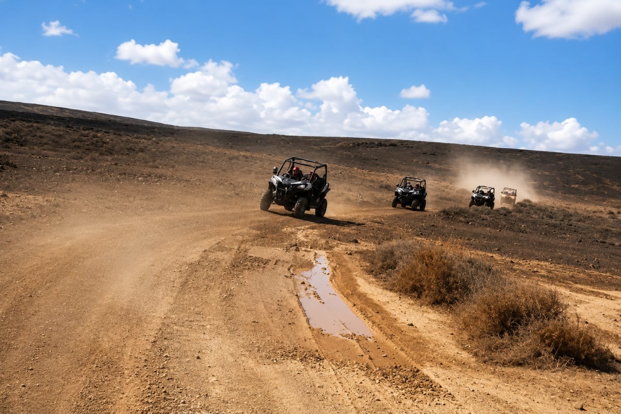 Three off-road buggies driving along a dusty volcanic trail during a buggy tour in Lanzarote.