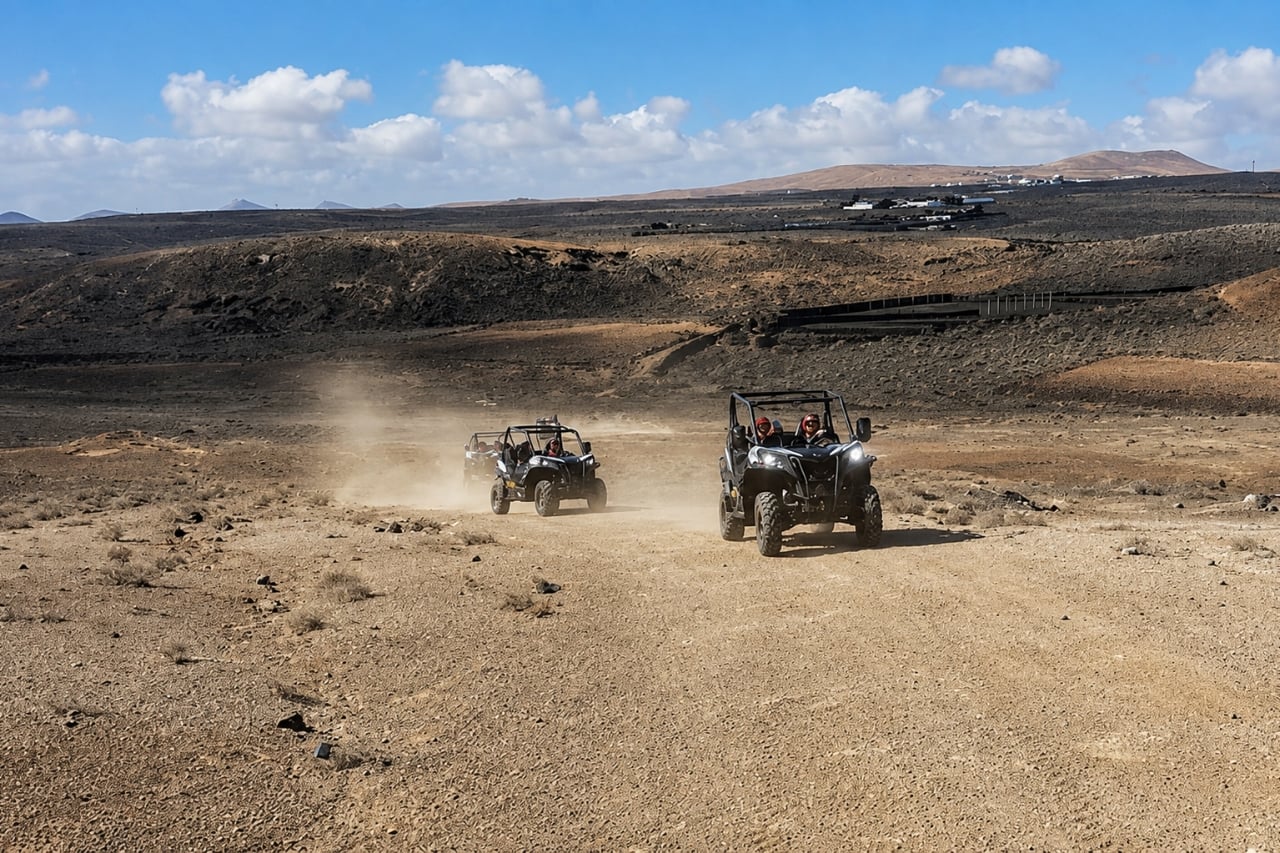 Two off-road buggies driving along a dusty trail through the volcanic landscape of Lanzarote