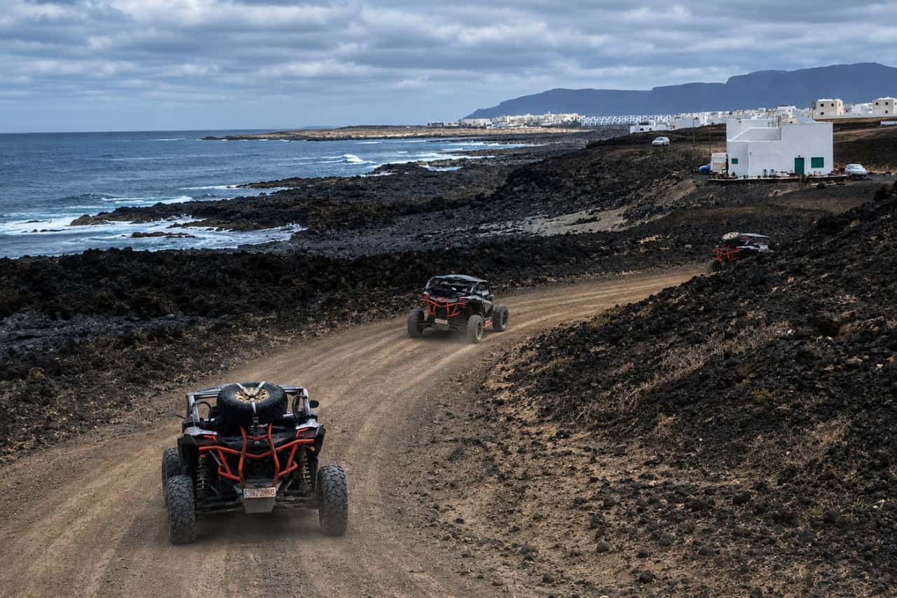 Buggies on a dirt trail beside the volcanic coast of Lanzarote