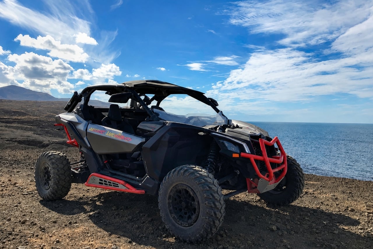 Black and red off-road buggy parked on rocky terrain overlooking the Atlantic Ocean in Lanzarote.