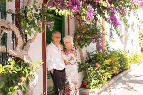 Elderly couple posing by colorful flowers in Puerto de Mogán, Gran Canaria