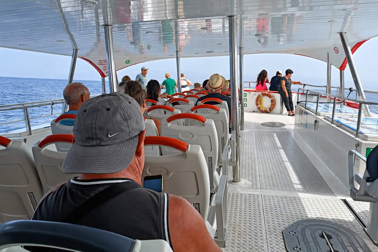 The shaded upper deck of the Multiacuatic catamaran with guests seated and standing, looking out to sea on a dolphin and whale watching trip in Gran Canaria.