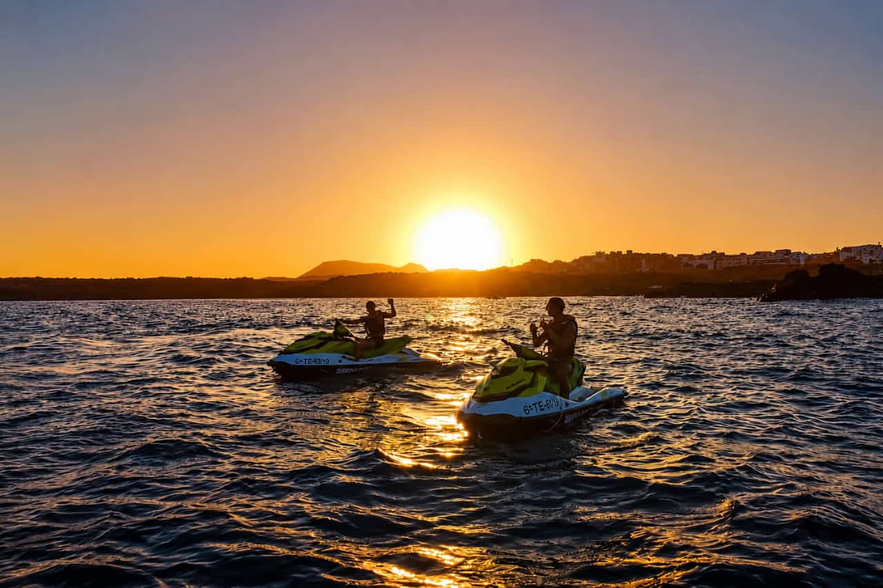Two jet skis riding across the ocean at sunset near Fuerteventura