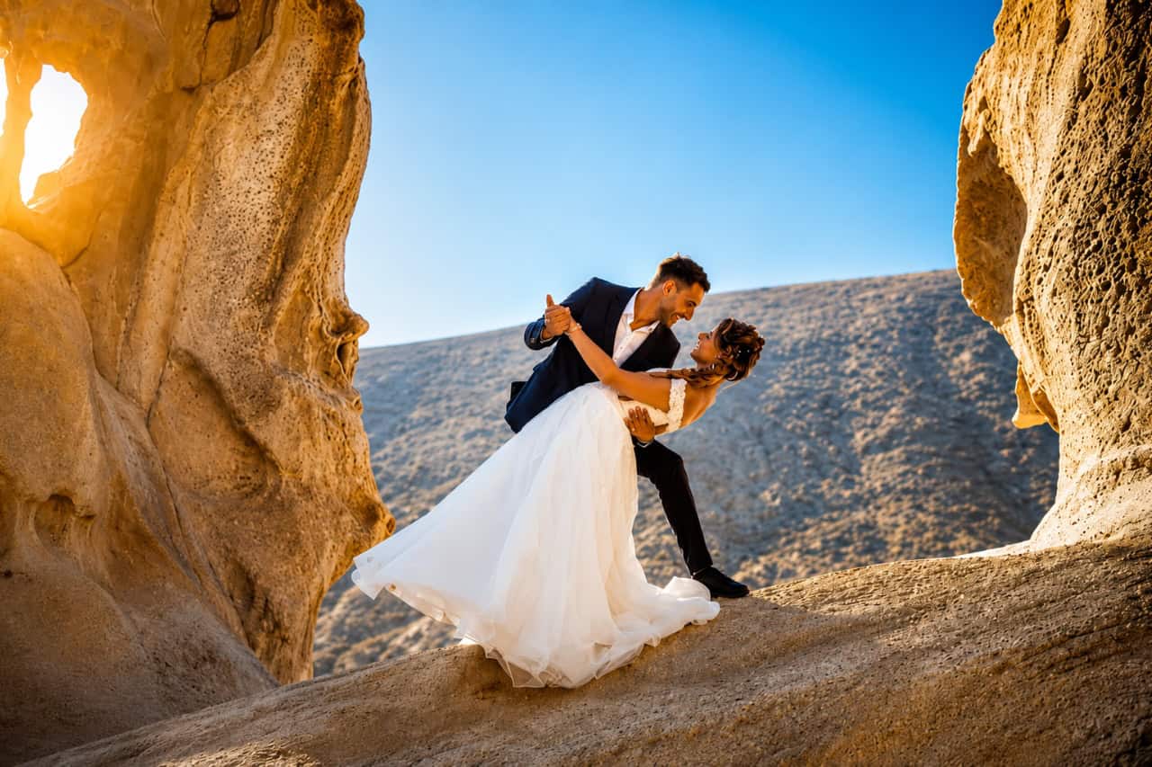 Newlywed couple embracing among dramatic volcanic rock formations during a wedding photoshoot in Fuerteventura.