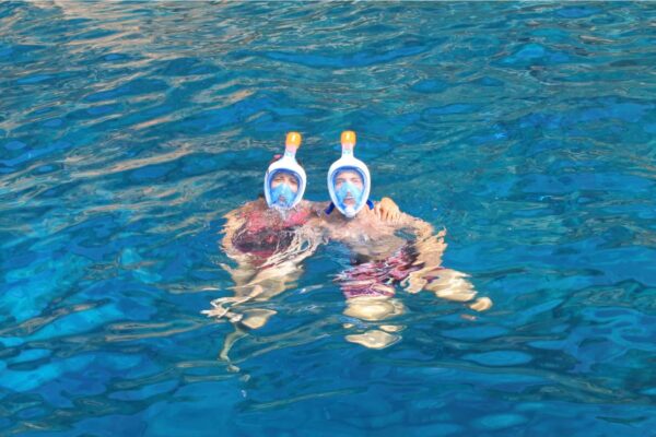 Twee mensen met een full-face snorkelmasker drijven in de kristalheldere oceaan van Gran Canaria.