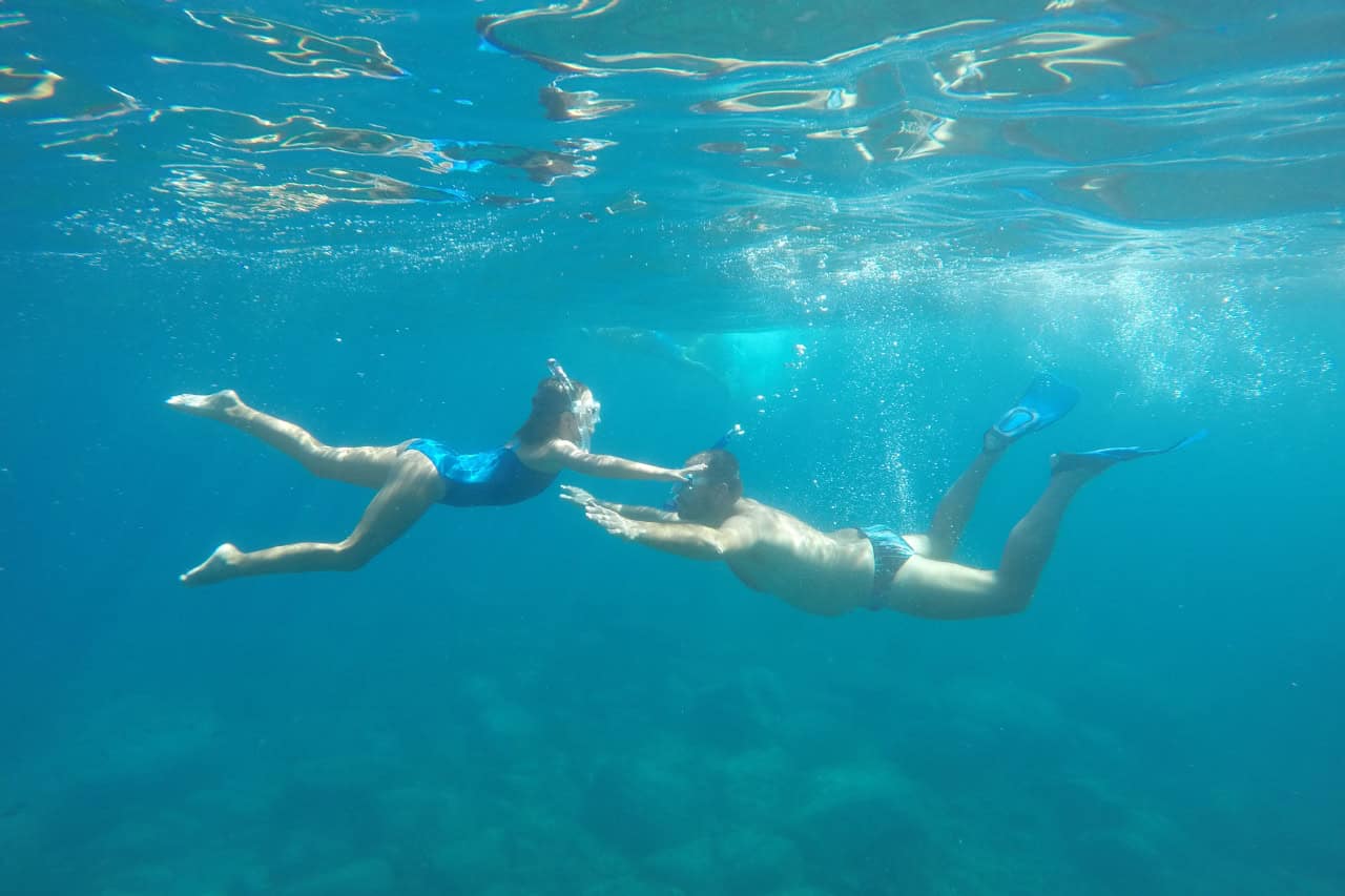Couple snorkeling underwater during a catamaran tour in the clear waters of Gran Canaria.