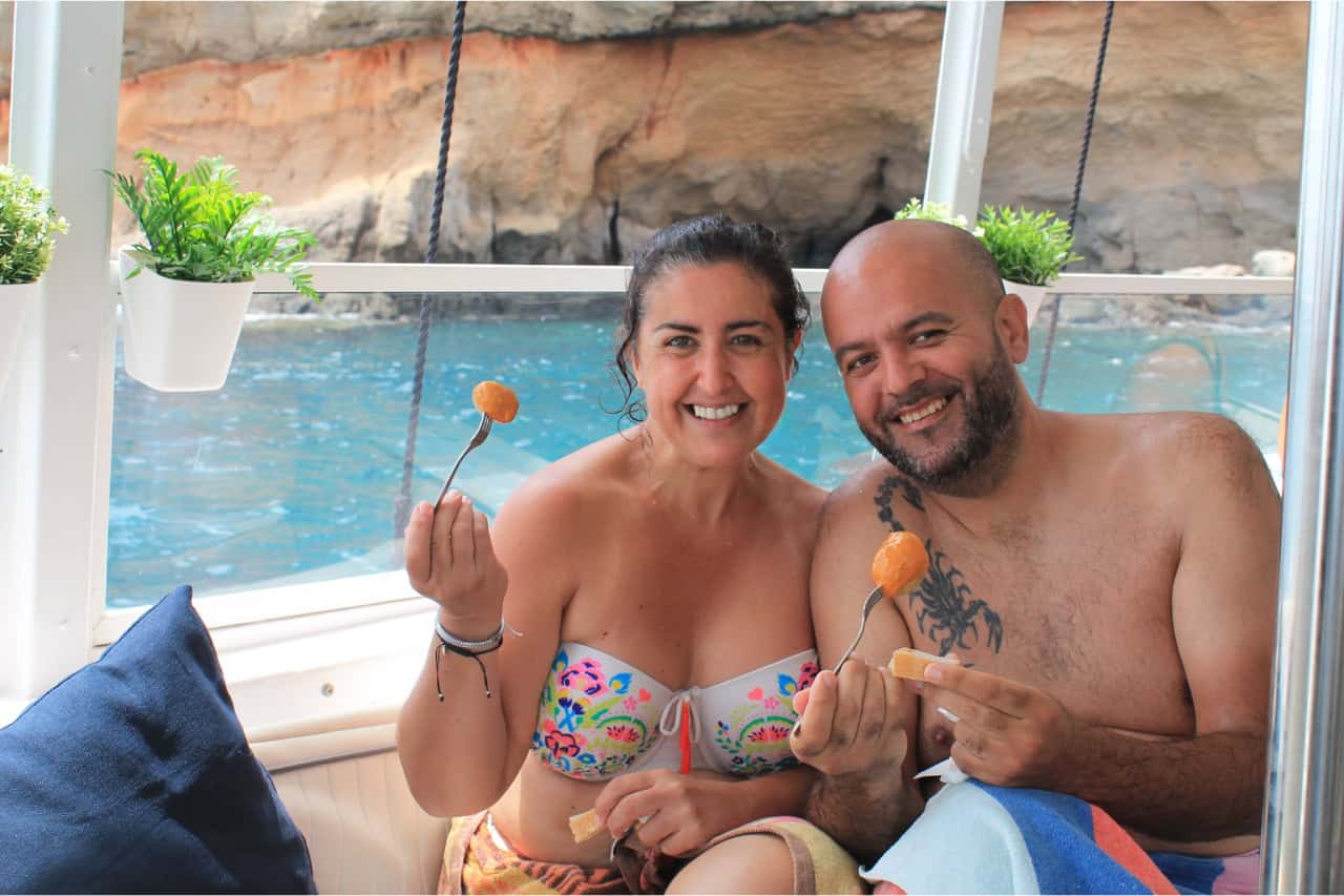 Happy couple sitting and enjoying snacks and refreshments on board a catamaran in Gran Canaria.