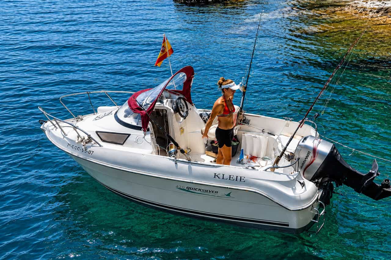 Woman standing aboard a private fishing boat near a rocky cove in Fuerteventura