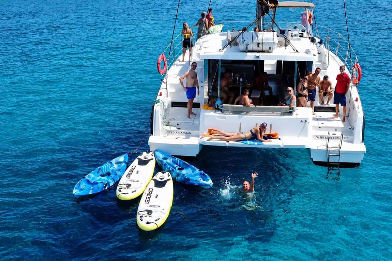 Guests swimming and using kayaks and paddleboards beside the catamaran