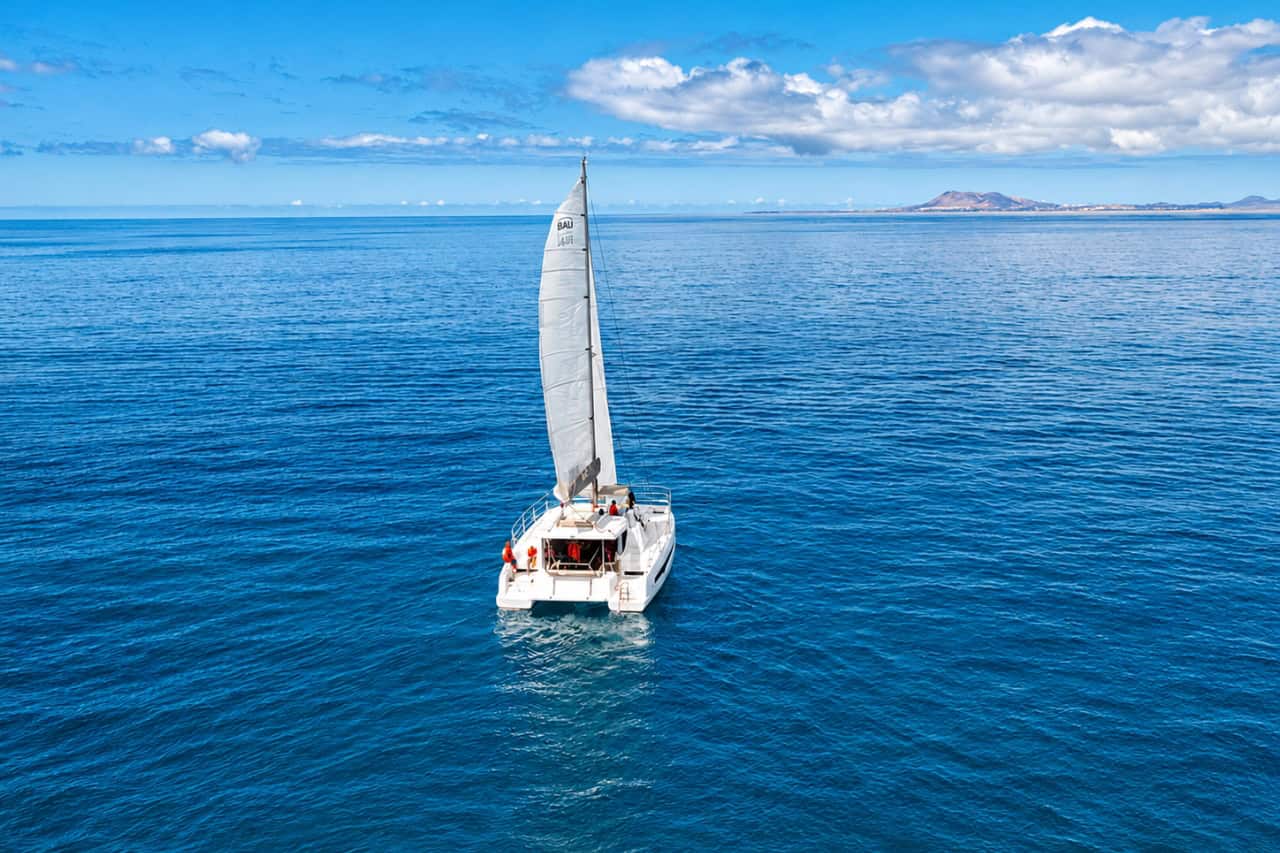 Aerial view of a luxury sailing catamaran cruising across the calm blue ocean near Fuerteventura.
