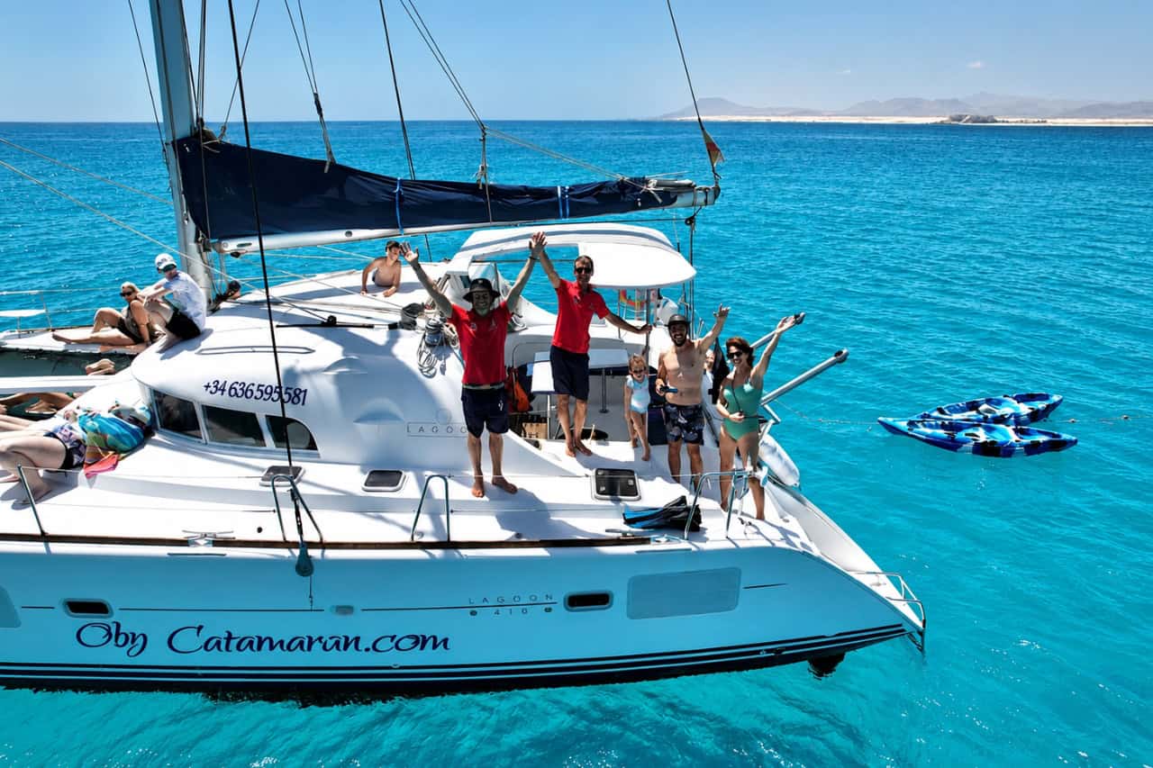 Guests waving from the deck of the private catamaran in turquoise water