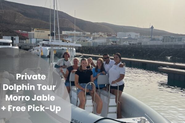 Turistas felices en una excursión privada en barco con delfines en el puerto de Morro Jable
