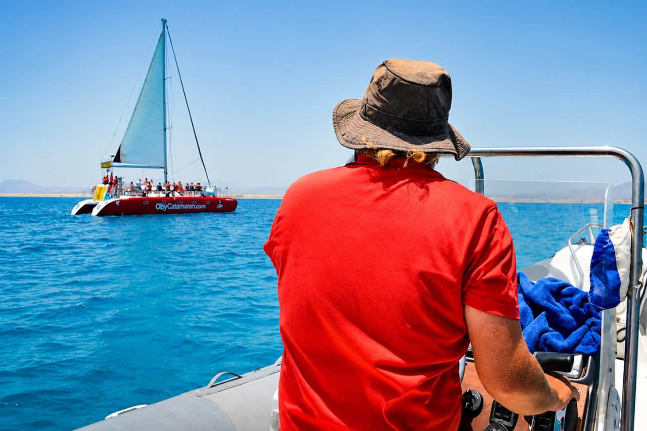 Passenger looking from a small boat toward a red catamaran near Fuerteventura
