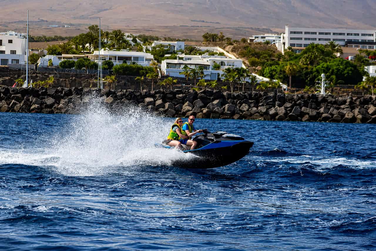 Pár jazdiaci na vodnom skútri blízko vulkanického pobrežia Lanzarote