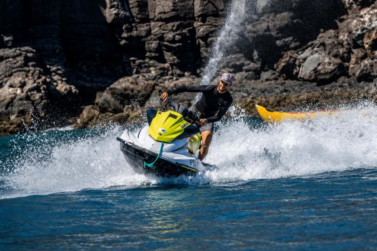 Rider turning a jet ski through the waves near the Lanzarote cliffs