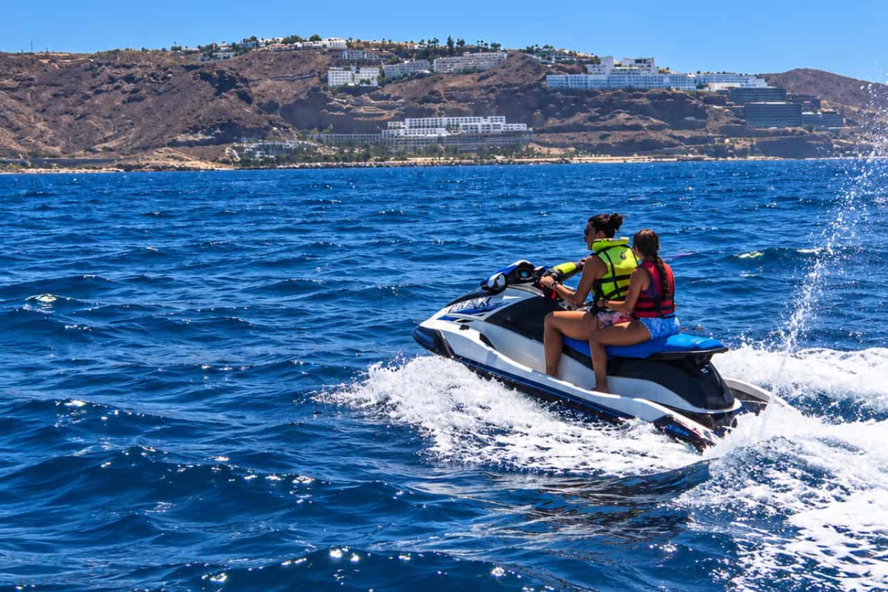 Two guests sharing one jet ski along the coast