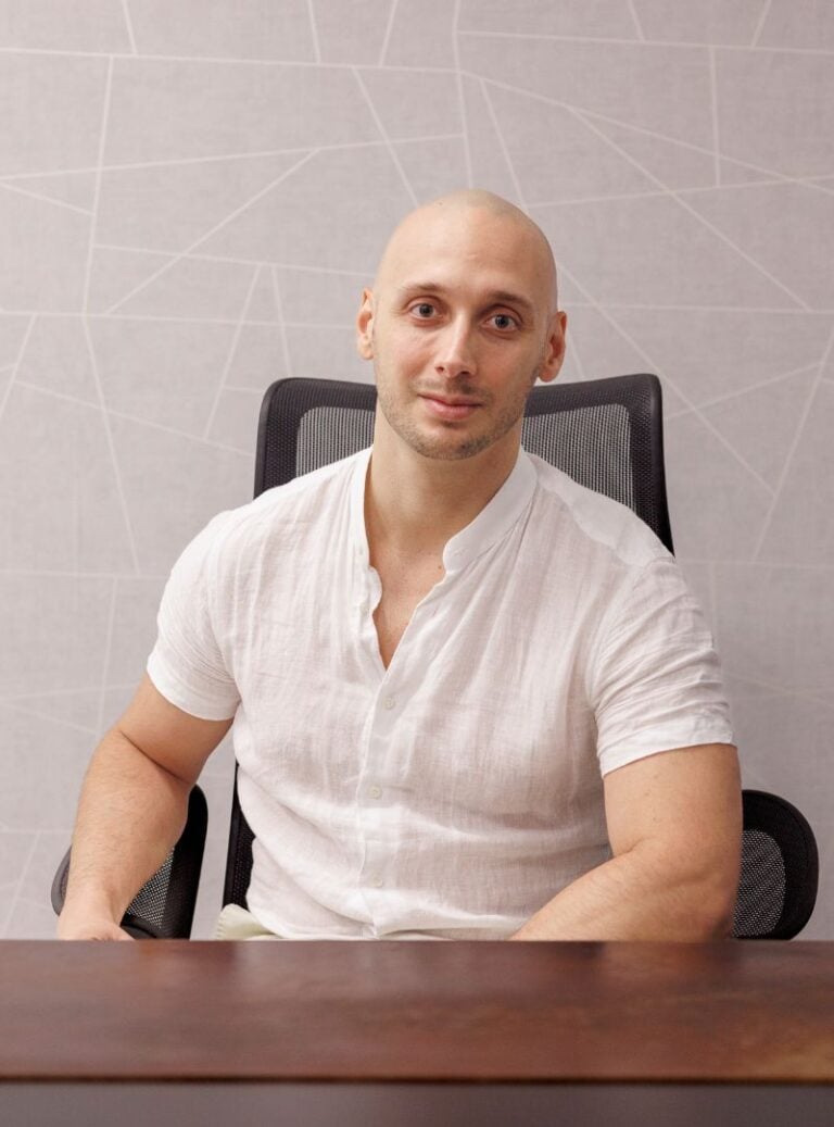 Náš generální ředitel Roy sedí u svého stolu a pilně pracuje v profesionálním kancelářském prostředí.