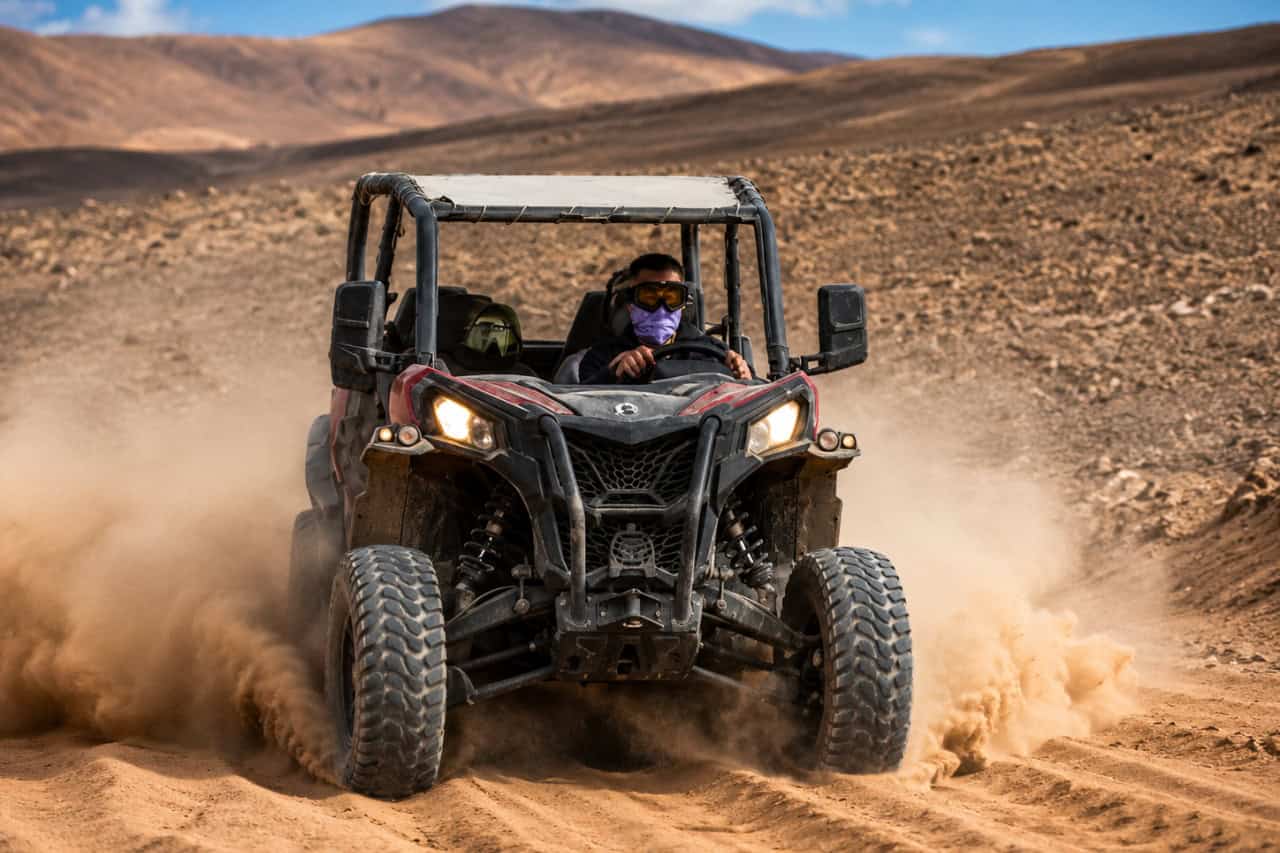 Driver wearing protective goggles while navigating a buggy along a dusty off-road route in Fuerteventura.