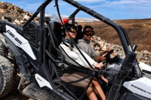 Two women wearing protective goggles while riding together in an off-road buggy in Fuerteventura.