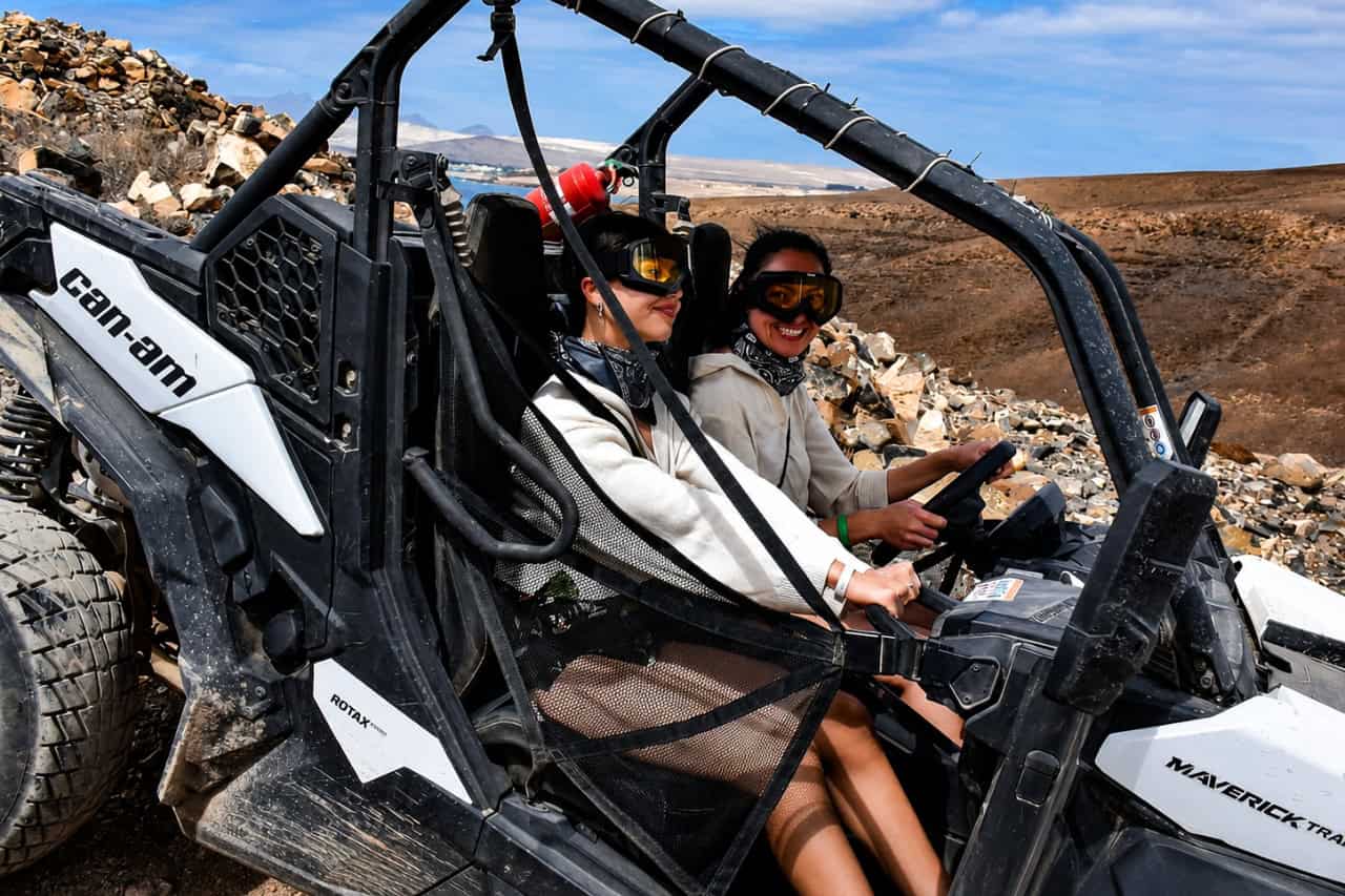 Two women wearing protective goggles while riding together in an off-road buggy in Fuerteventura.