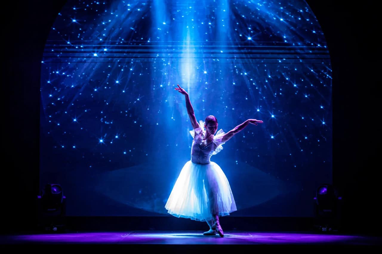 Ballet dancer performing under blue stage lights at History Evolution of Music in Tenerife