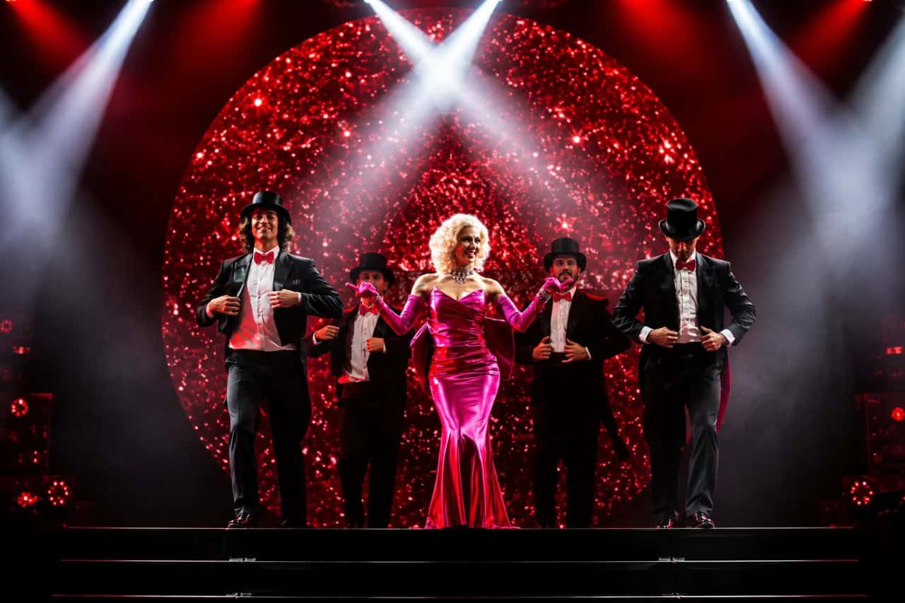 Cabaret-style performers on stage under spotlights during the History evening show in Tenerife