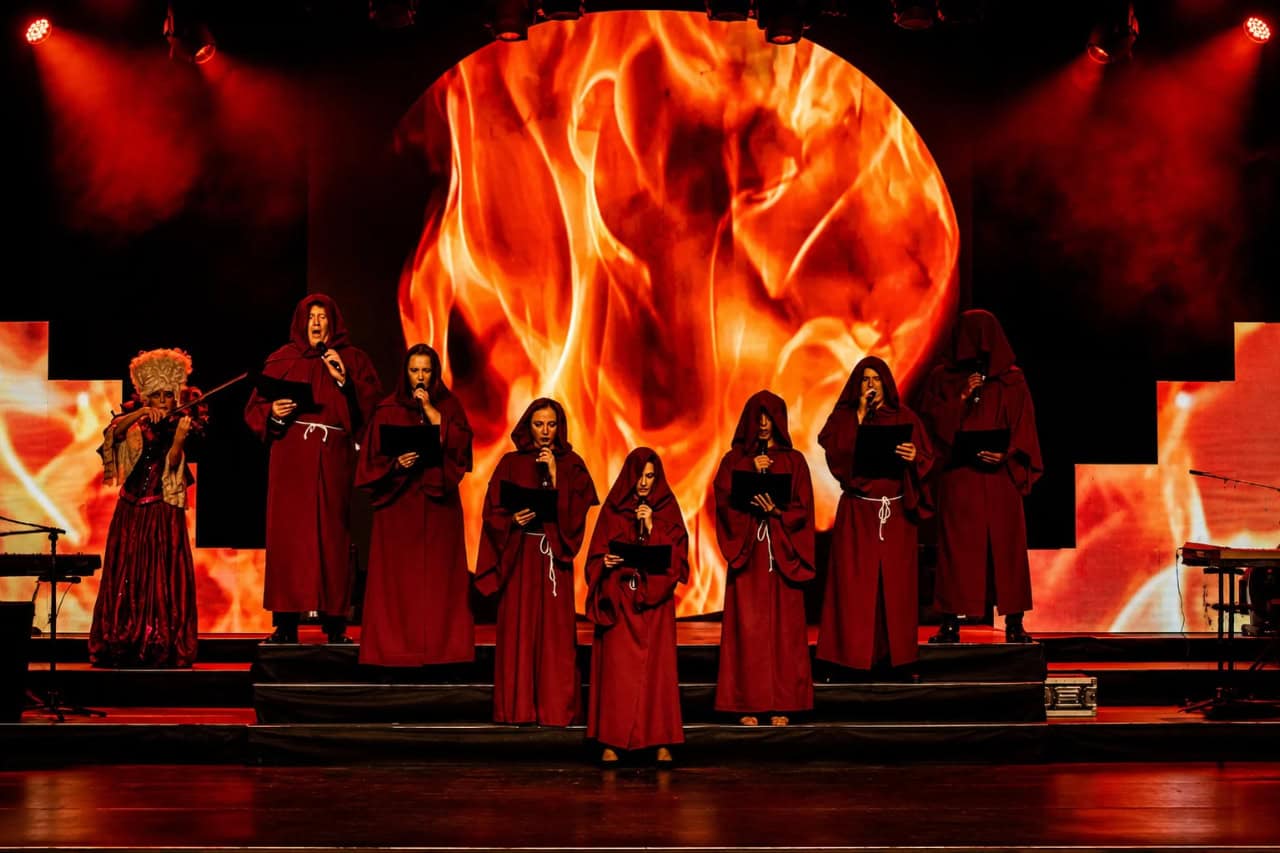 Performers in red costumes on stage with dramatic fire visuals during the Tenerife show