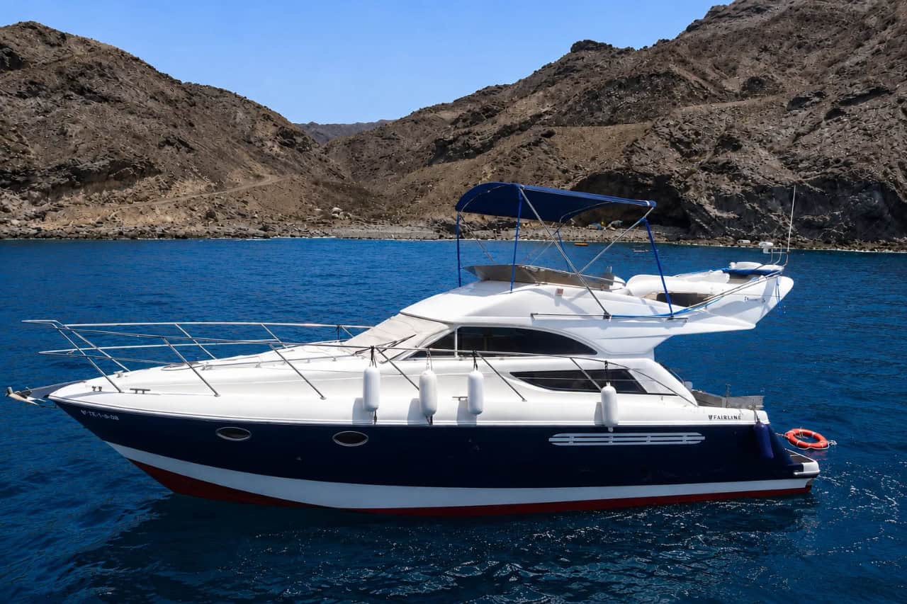 Motor yacht cruising beside the volcanic coastline of Gran Canaria