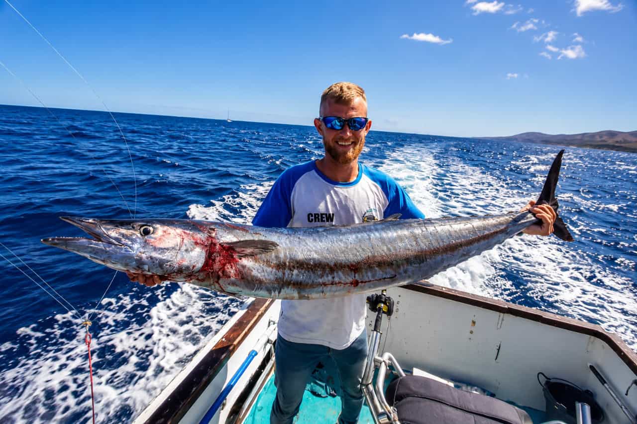 Crew member holding a large game fish aboard a boat during a big-game fishing trip off the coast of Lanzarote.