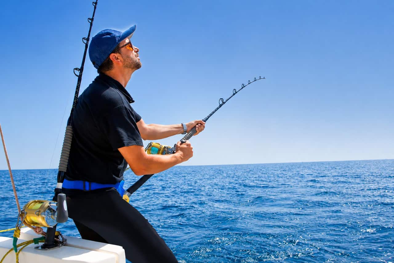 Man fighting a fish with a bent fishing rod during a big-game fishing trip off the coast of Lanzarote.