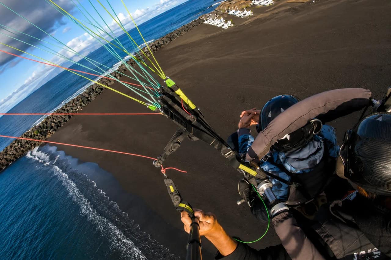 Tandem paragliding above a black sand beach on the coast of Tenerife