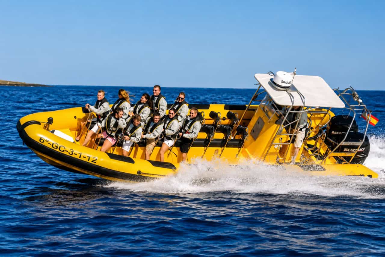Passengers wearing life jackets enjoying a high-speed yellow boat ride during a dolphin safari in Lanzarote.