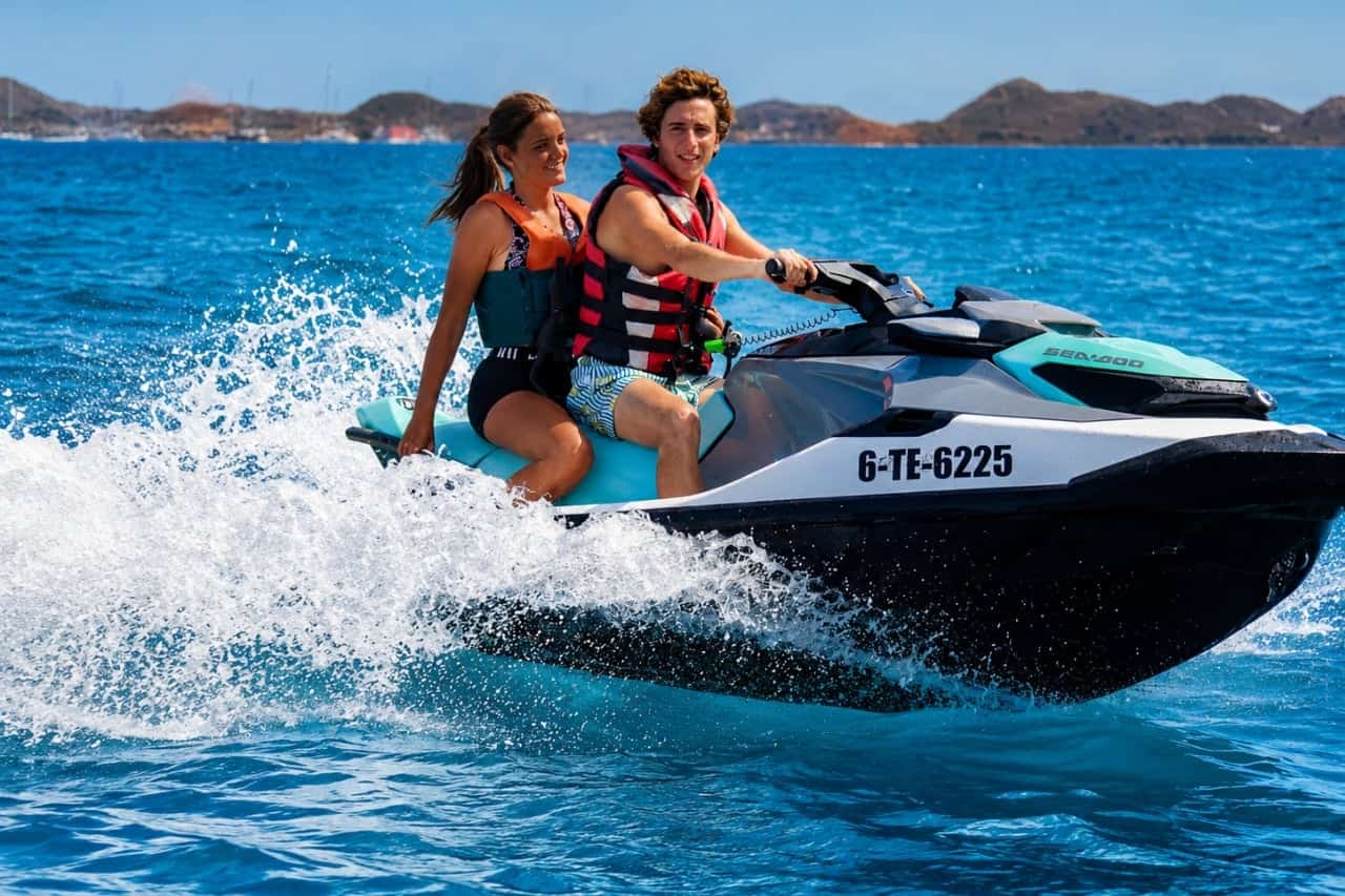 Couple wearing life jackets riding a jet ski across the clear blue waters of Fuerteventura.