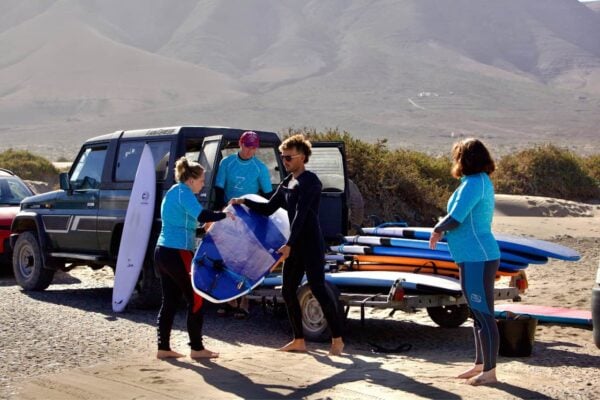 Elevii și instructorul de la școala de surf din Lanzarote pregătesc plăci de surf pentru lecții pe plaja Caleta de Famara