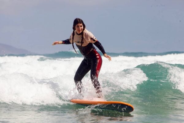 O studentă se bucură de lecții de surfing în Lanzarote, pe plaja Famara, prezentând valuri de surf pentru începători