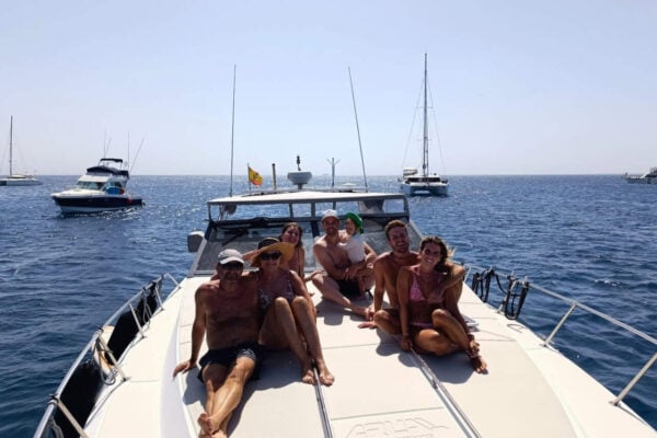 Srečna skupina, ki uživa na zasebnem izletu z jahto iz Playa Blanca in se sprošča na sončni palubi.