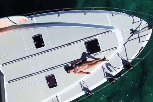 Nainen ottaa aurinkoa yksityisen jahdin kannella romanttisen sunset cruise-retken aikana Playa Blancassa.